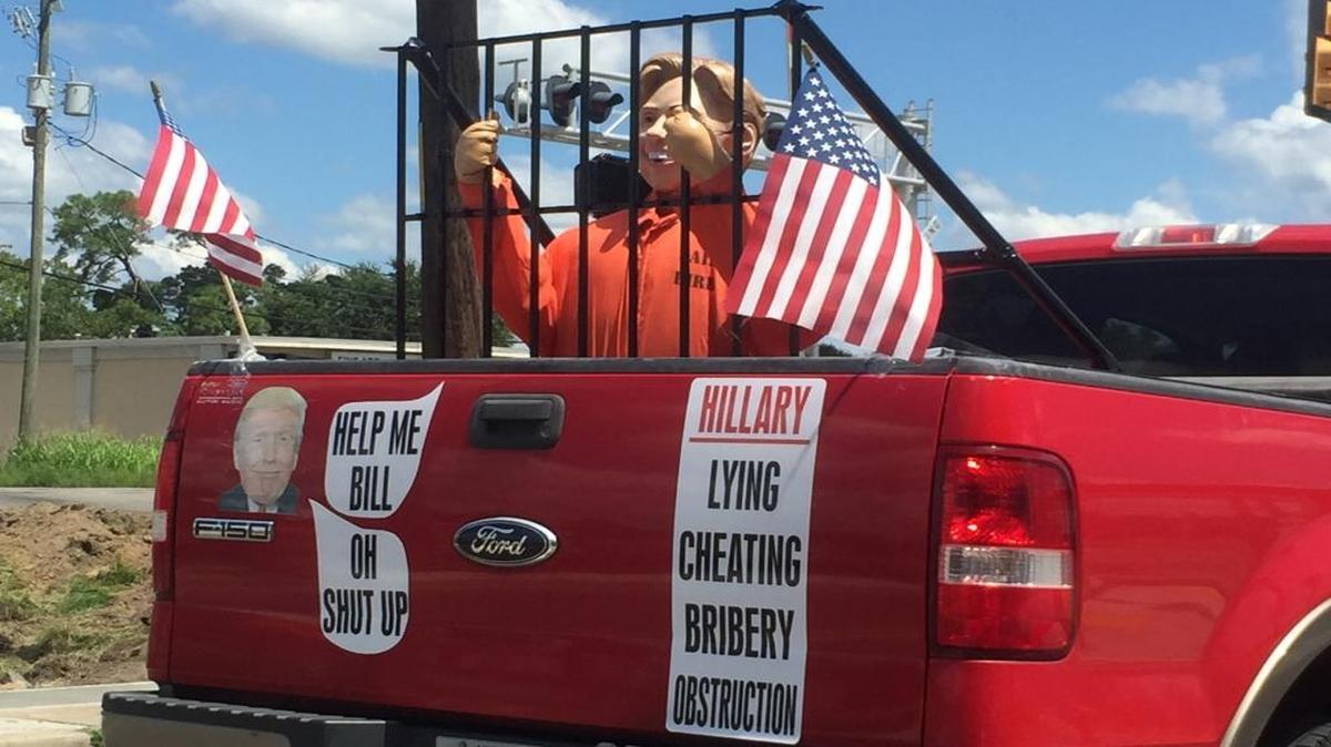 A Hillary Clinton statue is seen behind ‘prison bars’ in the bed of a pickup truck in Biloxi.