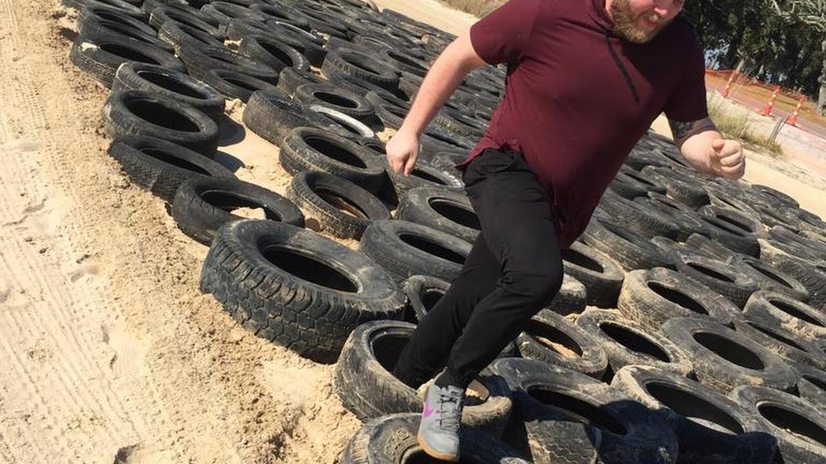 Justin Mitchell runs through tires while training for Battle on Buffett Beach in Pascagoula.