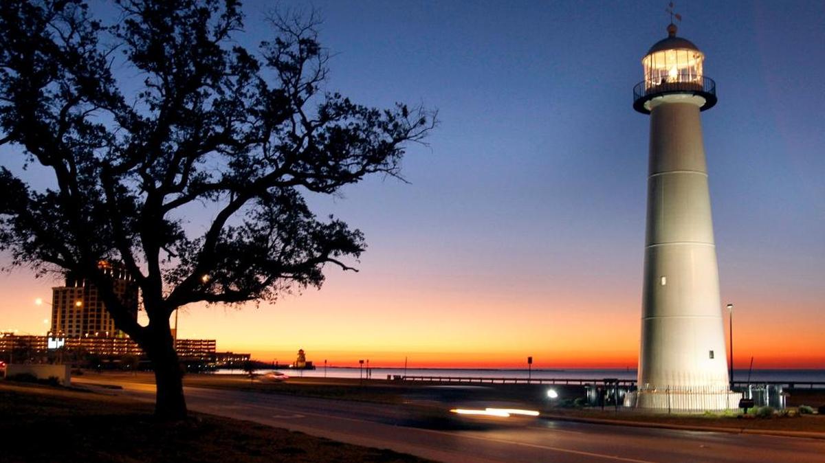 A lone car passes the Biloxi Lighthouse at sunrise.