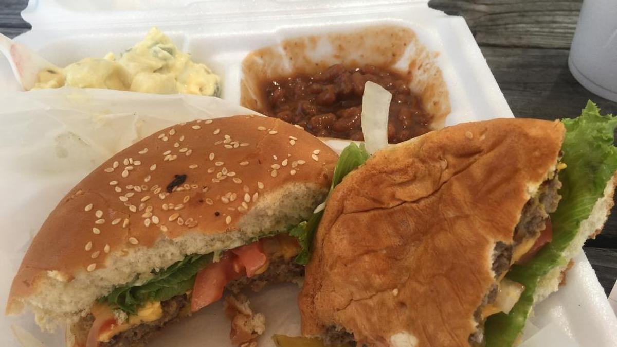 A cheeseburger is served with potato salad and baked beans at The Cabin Store in Wiggins.