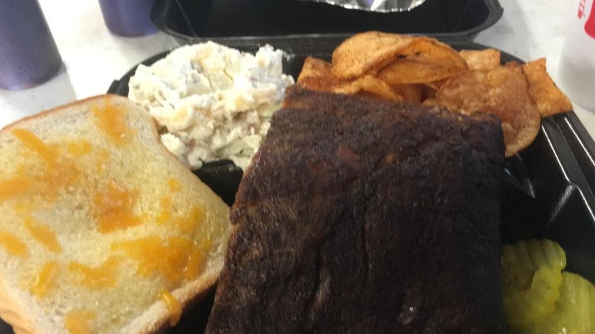 A plate order at Belly Up Barbecue in Gulfport comes with meat, two sides, a piece of bread and pickles. This is a four-rib Baby Back Plate with potato salad and housemade chips.