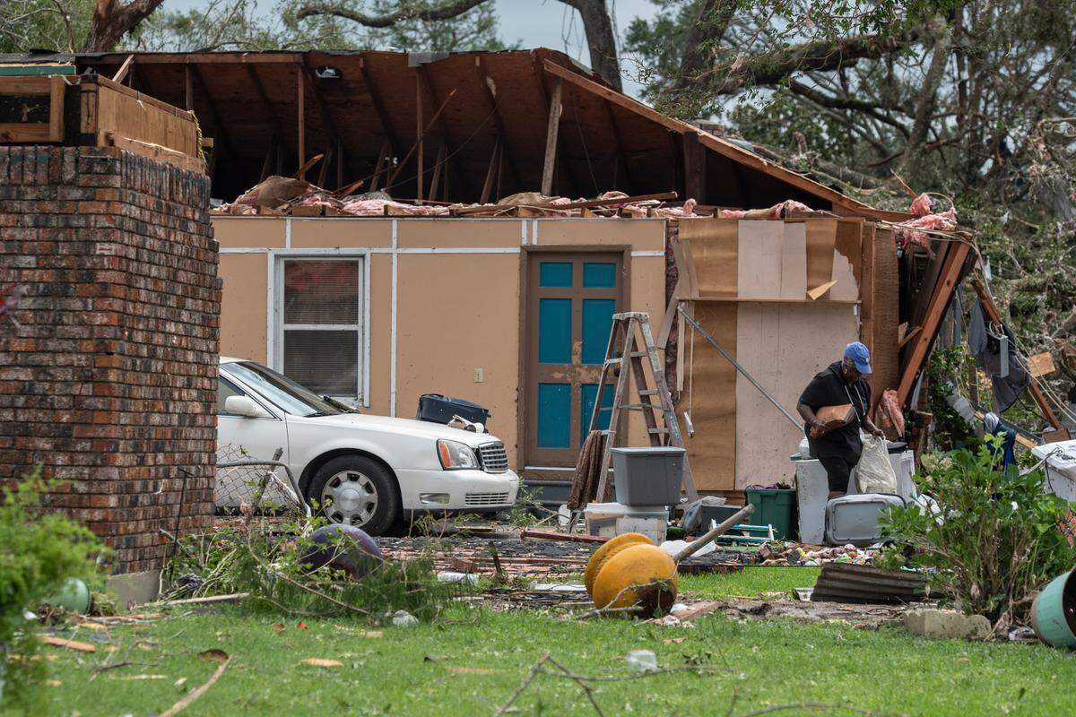 A woman salvages personal belongings from a damaged home in Moss Point on Tuesday, June 20, 2023, after a tornado tore through the town on Monday.