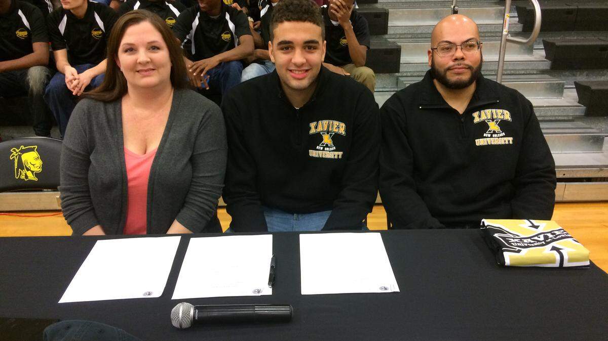 D'Iberville senior Evan Howard, center, signed with Xavier-New Orleans on Wednesday. He surrounded by his mom, Erica, and father, Isaac.