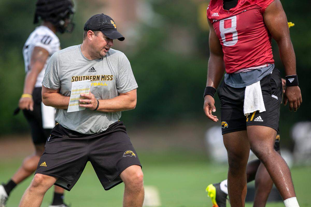 Southern Miss Coach Will Hall shows Trey Lowe a move during the first day of training camp on Friday, Aug. 6, 2021.