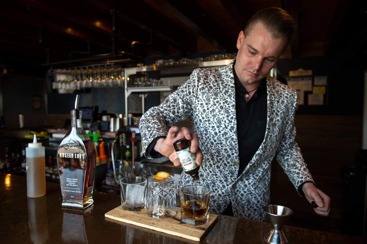 Bartender Jonathan “Jelly” Kelly makes the “Jelly” drink — an old fashioned with Angels Envy bourbon, smoked hickory apricot bitters, honey simple syrup, luxardo cherries and orange peel — at Rackhouse Steaks and Spirits in Gulfport on Tuesday, April 11, 2023.
