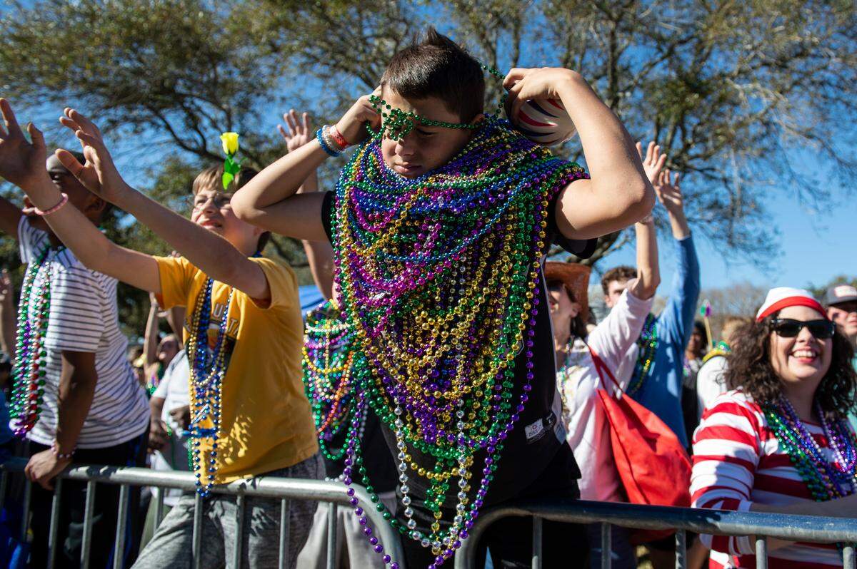 A young parade watcher adds another string of beads to his collection during the Gulf Coast Carnival Association Mardi Gras Parade in Biloxi on Tuesday, March 1, 2022.