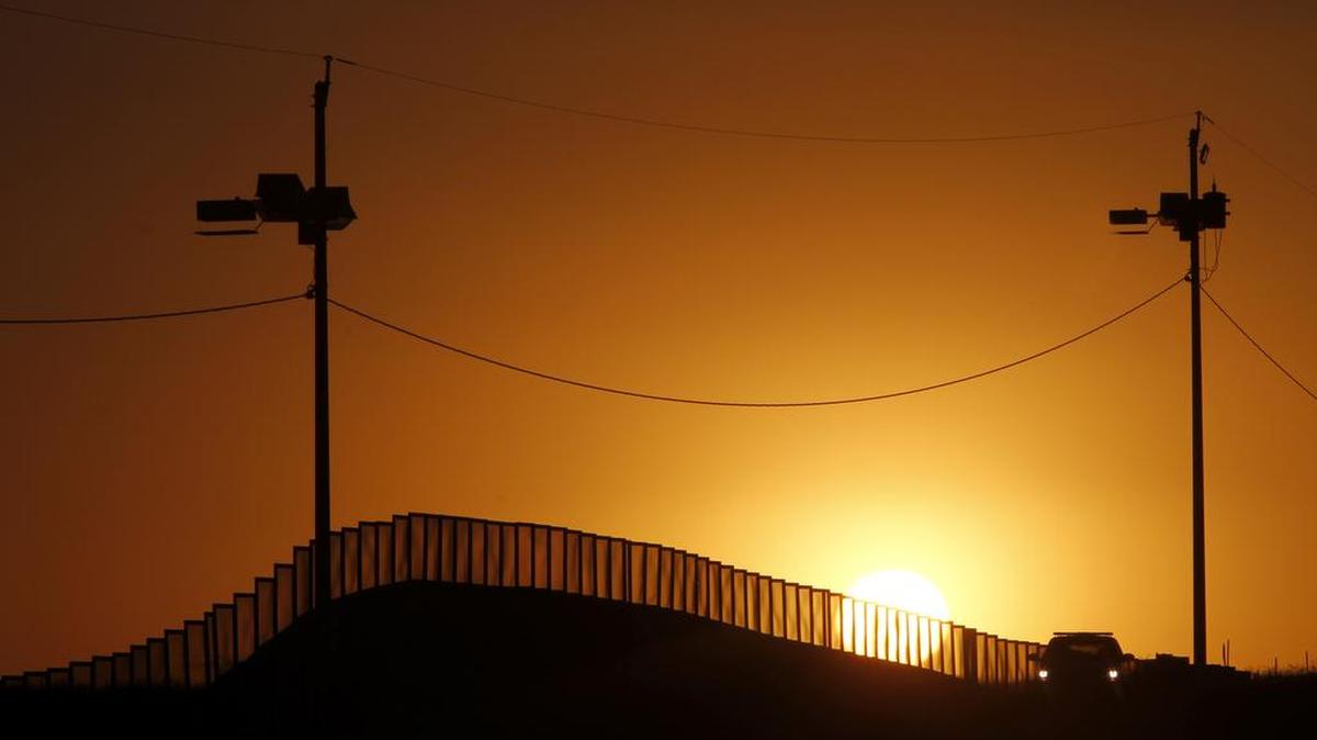 Sunset at the U.S.-Mexico border in Naco, Ariz., where a Border Patrol agent in his car keeps an eye on activity in 2013.
