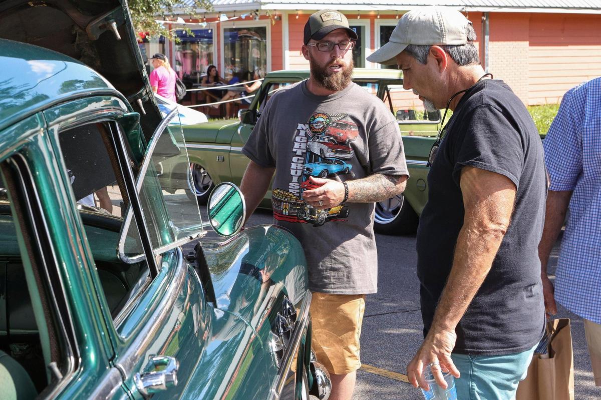 An owner of a Cruisin’ car talks shop with a spectator in Ocean Springs during the Cruisin’ The Coast Block Party 2021. 