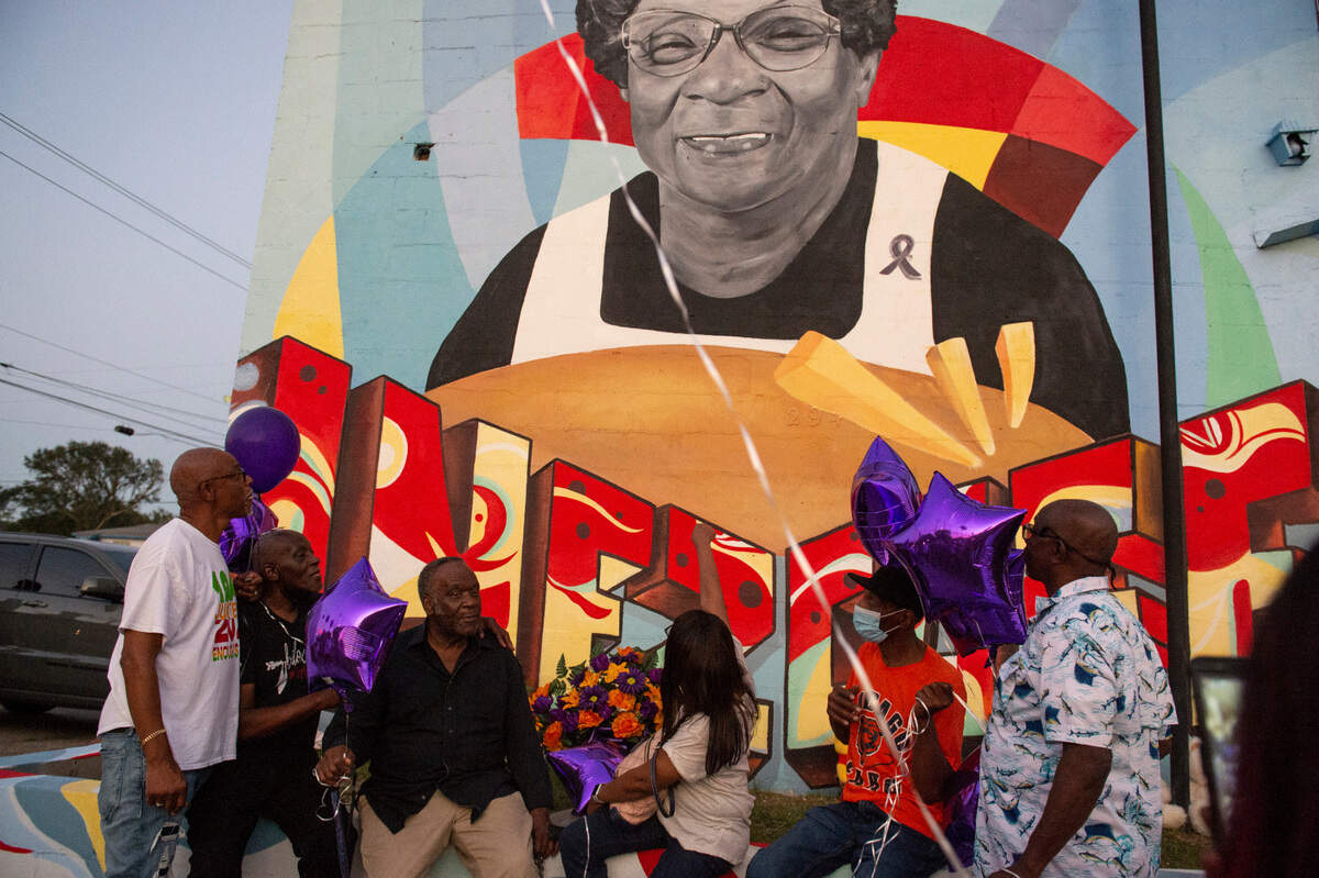 Inez Thomas’ children and siblings look up at her mural painted on the side of her former restaurant during a balloon release in her honor in East Biloxi on Friday, Oct. 22, 2021.
