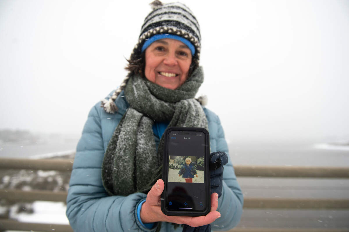 Jennifer Wright stands on the Fort Bayou Bridge during a winter storm on Tuesday, Jan. 21, 2025, and shows a photo of her daughter, Emily, during a winter storm in 1996. Wright says the photo is the last time before Tuesday she’s seen snow on the Mississippi Coast.