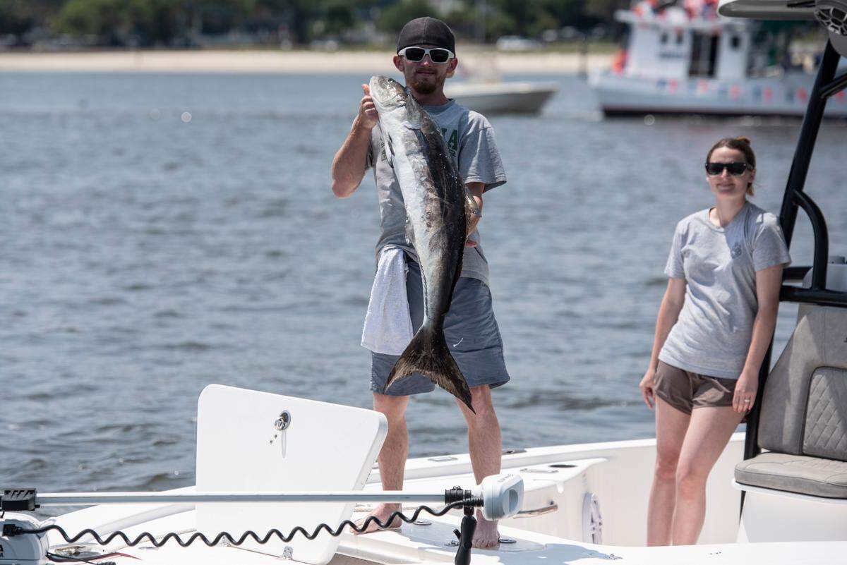 A man holds up a fish to be blessed during the Blessing of the Fleet in Biloxi on Sunday, May 28, 2023.
