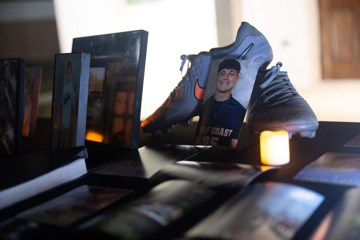 Photos of Landon Perry sit next to a pair of his soccer cleats.
