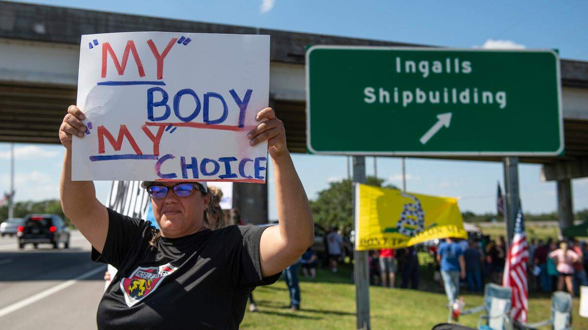 Louby Edwards, of Mobile, stands on the side of Highway 90 during a protest of Ingalls’ vaccine mandate in Pascagoula on Friday, Oct. 8, 2021.
