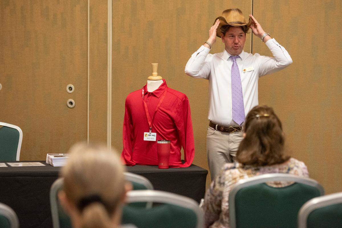 Dane Batley, the general manager of the new Mississippi Buc-ee’s location, demonstrates employee uniforms during a hiring fair for the chain at the Mississippi Coast Coliseum on Wednesday, April 2, 2025.