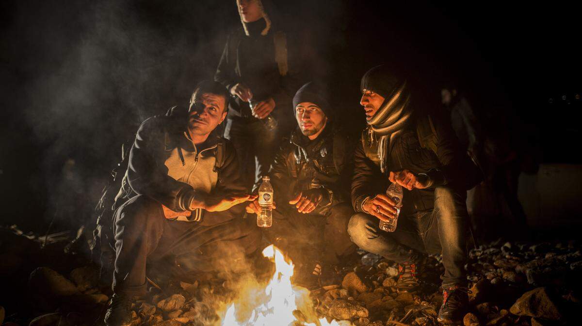 A group of men try to warm up next to a bonfire on a beach shortly after their arrival in a dinghy, with other refugees and migrants, from the Turkish coast to the northeastern Greek island of Lesbos, on Monday, Nov. 30, 2015. The International Organization for Migration said almost 900,000 people fleeing conflict and poverty in the Middle East, Africa and Asia have entered Europe this year seeking sanctuary or jobs. More than 600,000 have entered through Greece, many after making the short sea crossing from Turkey. (AP Photo/Santi Palacios)