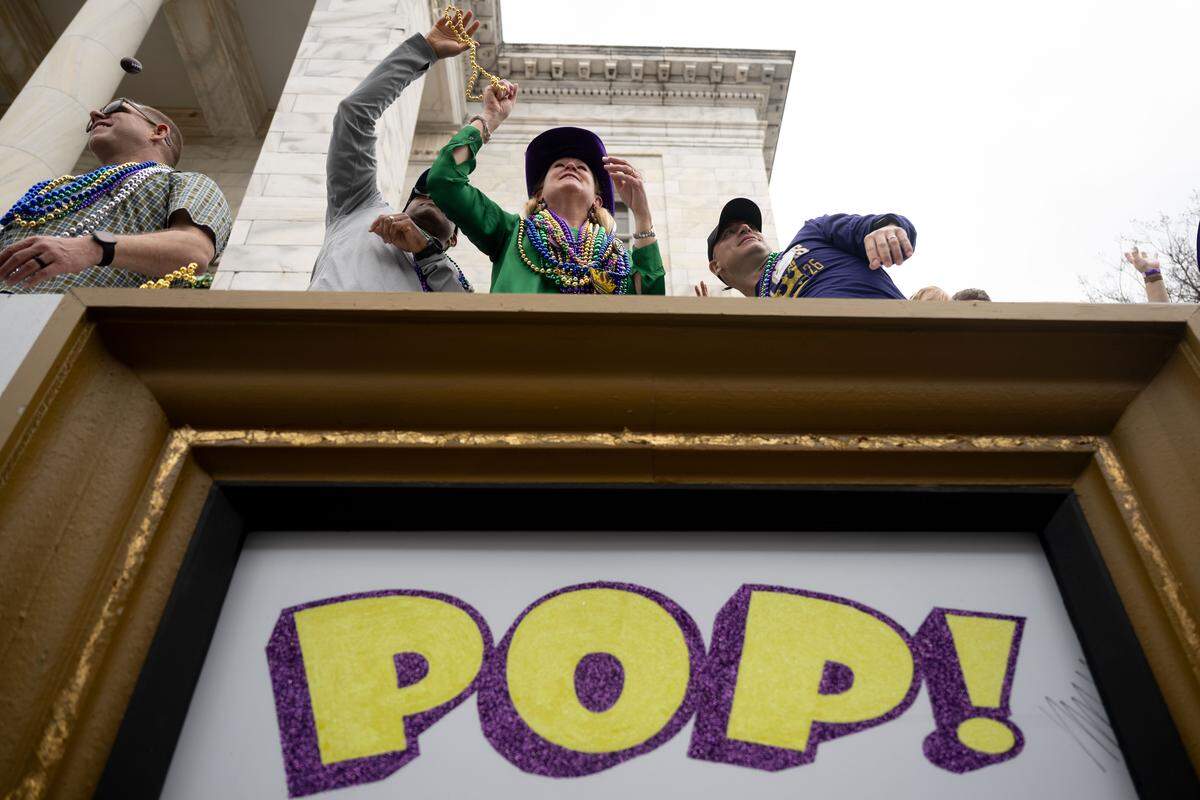 Crowd members catch Mardi Gras beads.