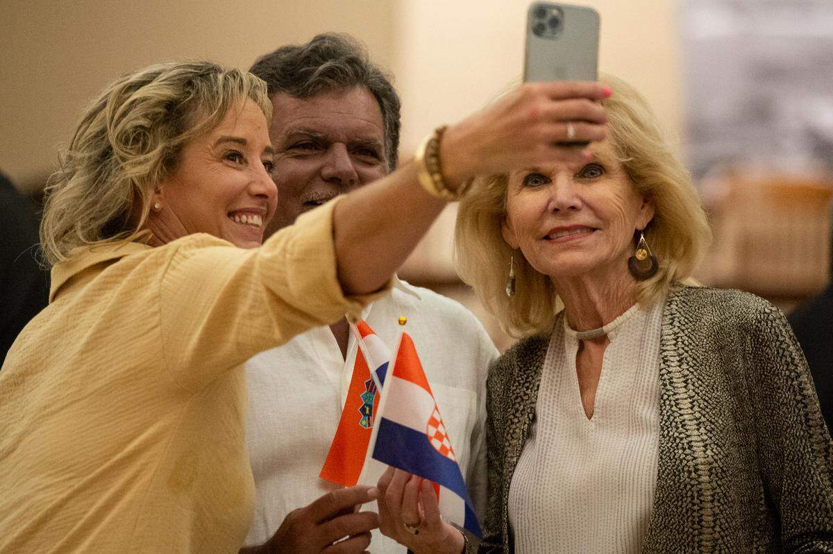 Members of the Croatian American Cultural Center take selfies with Croatian flags during an event welcoming Croatian President Zoran Milanović at the Croatian American Cultural Center in Biloxi, Miss. on Friday, Sept. 22, 2023.