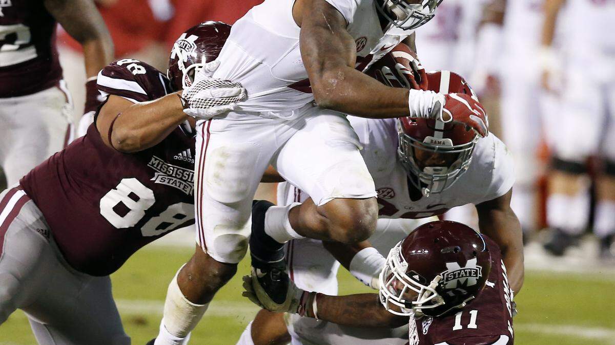 Alabama running back Derrick Henry (2) fights offs an attempted tackles by Mississippi State defensive back Kivon Coman (11) and defensive lineman Nick James (88) on his way to a short gain during the second half of an NCAA college football game in Starkville, Miss., Saturday, Nov. 14, 2015. No. 3 Alabama won 31-6. (AP Photo/Rogelio V. Solis)