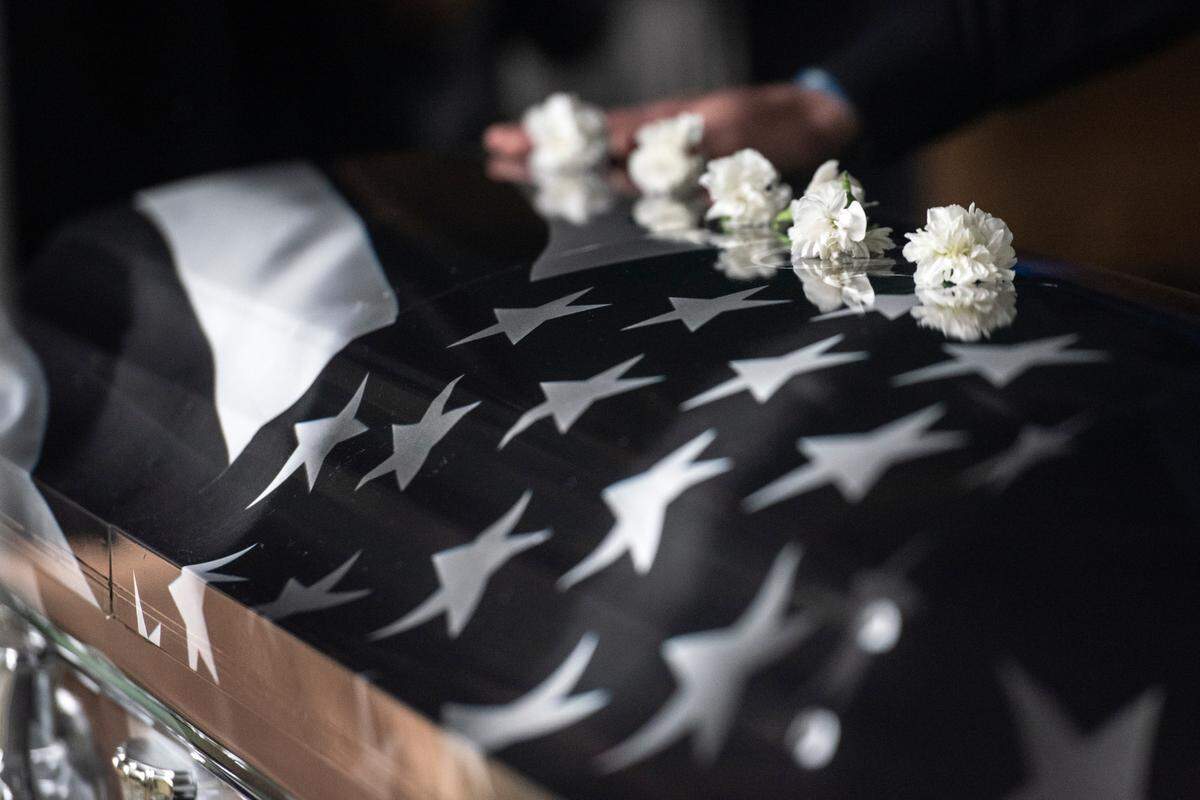 Mourners lay white flowers on the caskets of Bay St. Louis police officers Sgt. Steven Robin and Branden Estorffe at Gardens of Memory cemetery in Bay St. Louis on Wednesday, Dec. 21, 2022. Robin and Estorffe were killed responding to a call at a Motel 6 on Dec. 14.