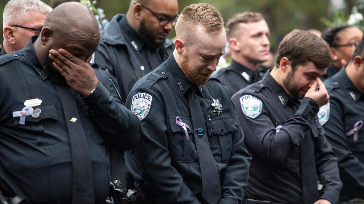 Bay St. Louis police officers react as Capt. Rachel Jewell calls in the last radio call at the gravesite of Bay St. Louis police officers Sgt. Steven Robin and Branden Estorffe at Gardens of Memory cemetery in Bay St. Louis on Wednesday, Dec. 21, 2022. Robin and Estorffe were killed responding to a call at a Motel 6 on Dec. 14.