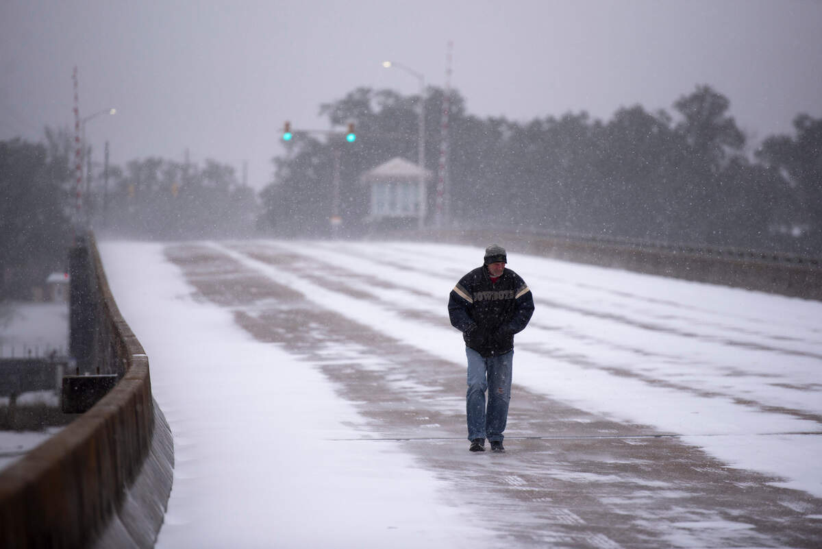 A man walks through the snow along the Fort Bayou Bridge during a winter storm on the Mississippi Coast on Tuesday, Jan. 21, 2025.