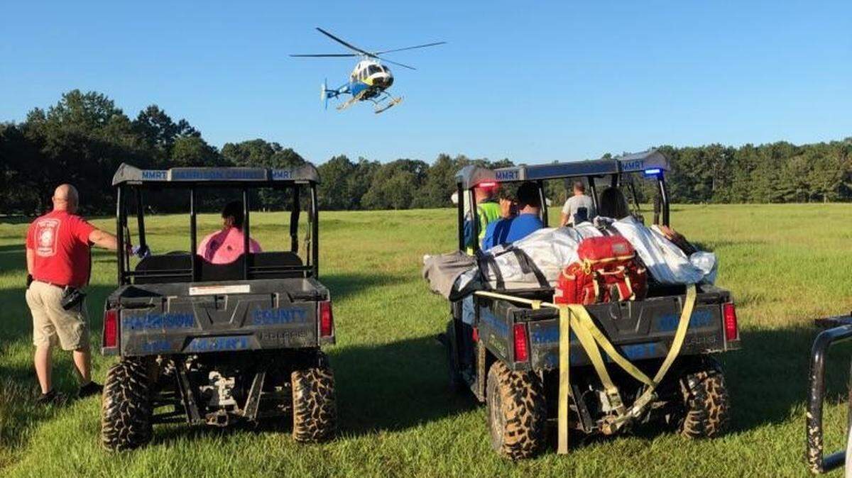 Rescues watch a helicopter take an injured woman to a trauma center in Mobile after a ATV crash in Harrison County.