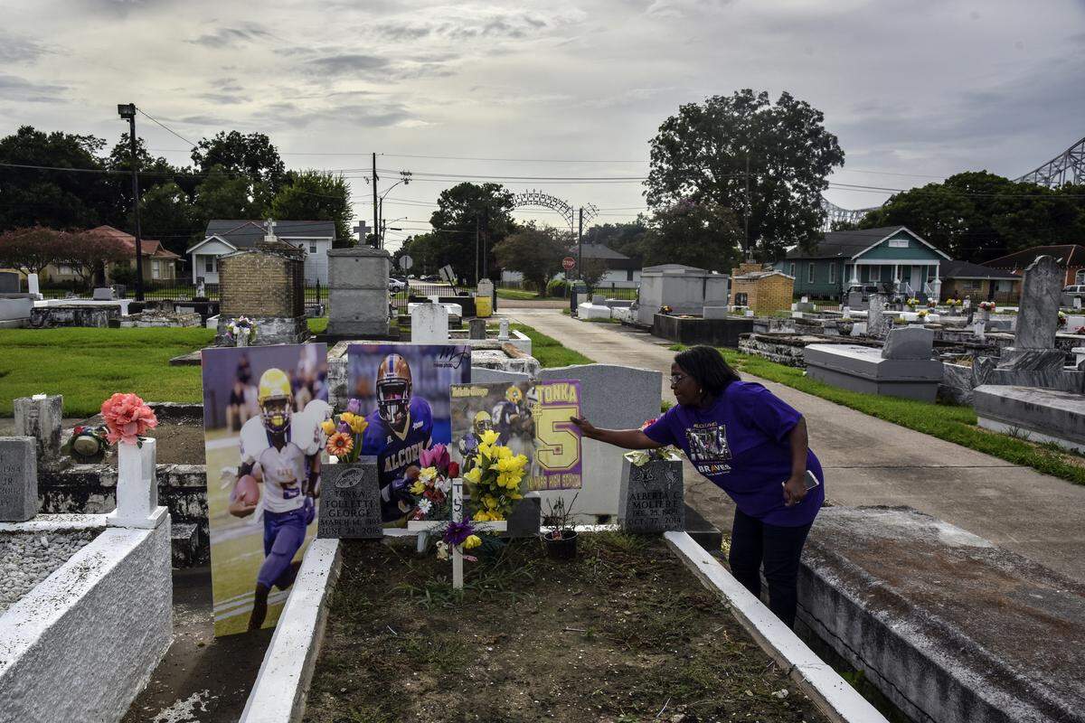 Rhonda George decorates the gravesite of her son, Tollette “Tonka” George, at McDonoghville Cemetery.