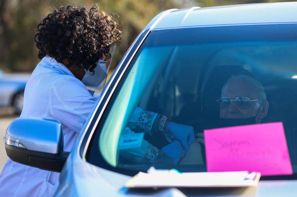 Monsignor James McGough, 87, receives the Moderna coronavirus vaccine from Coastal Family Health Clinic during a drive-up appointment at the Kroc Center in Biloxi Wednesday, Jan. 13, 2020.
