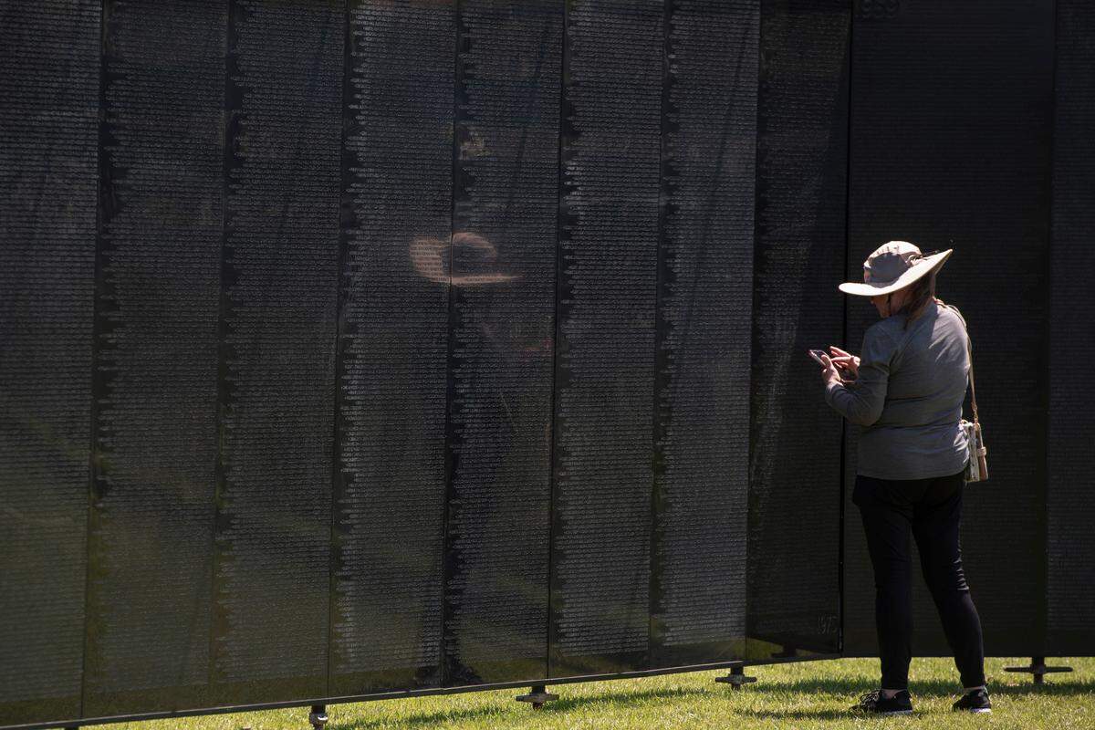Visitors look at names on The Wall That Heals, a traveling three-quarter scale replica of the Vietnam Veterans Memorial in D.C., while it is on display at the D’Iberville Sports Complex in D’Iberville on Thursday, April 10, 2025.