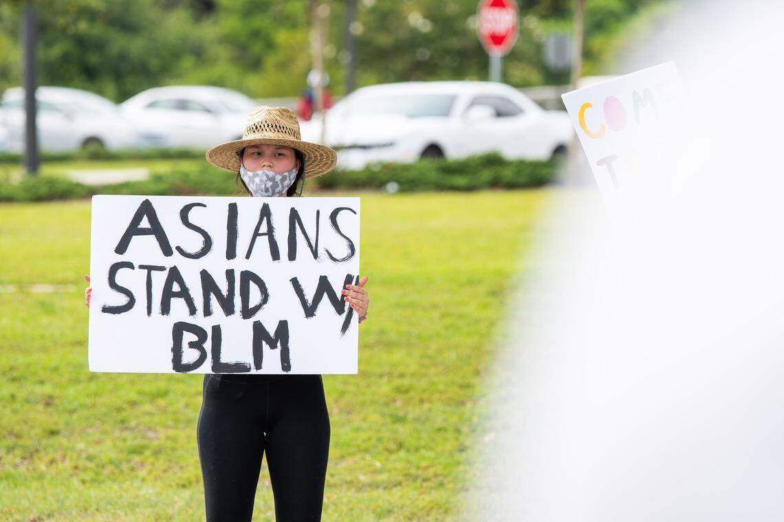 A protester holds a sign saying Asians stand with BLM (Black Lives Matter).