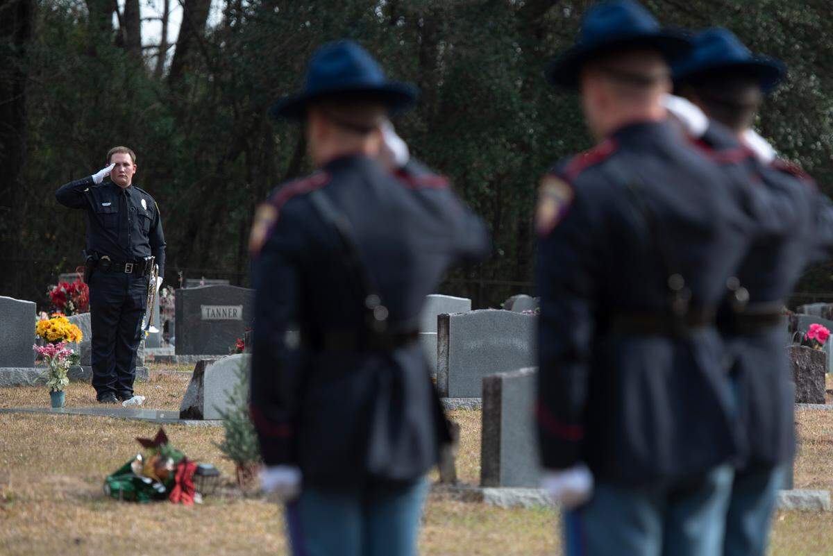 Honor guard and a trumpet player salute during a graveside service for George County Sheriff’s Deputy Jeremy Malone at Tanners Cemetery in George County on Friday, Jan. 12, 2024.