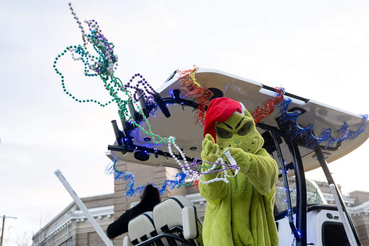 The Grinch tosses Mardi Gras beads from a float during the Champions Christmas Parade in Gulfport on Monday, Dec. 8, 2025.
