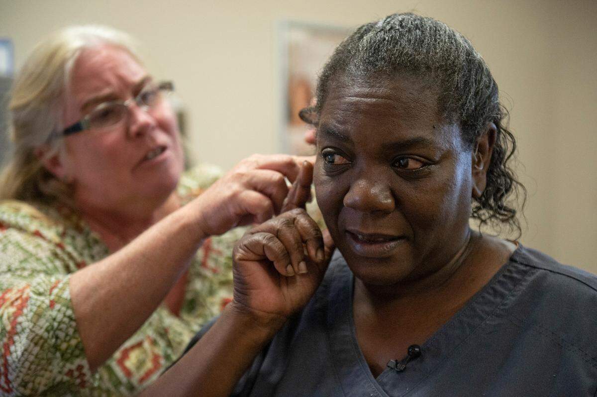 The receptionist at Miracle Ear in Gulfport helps Libby Riley adjust her hearing aids on Wednesday, April 20, 2022. Riley, who had never worn hearing aids, was able to hear clearly for the first time with them.