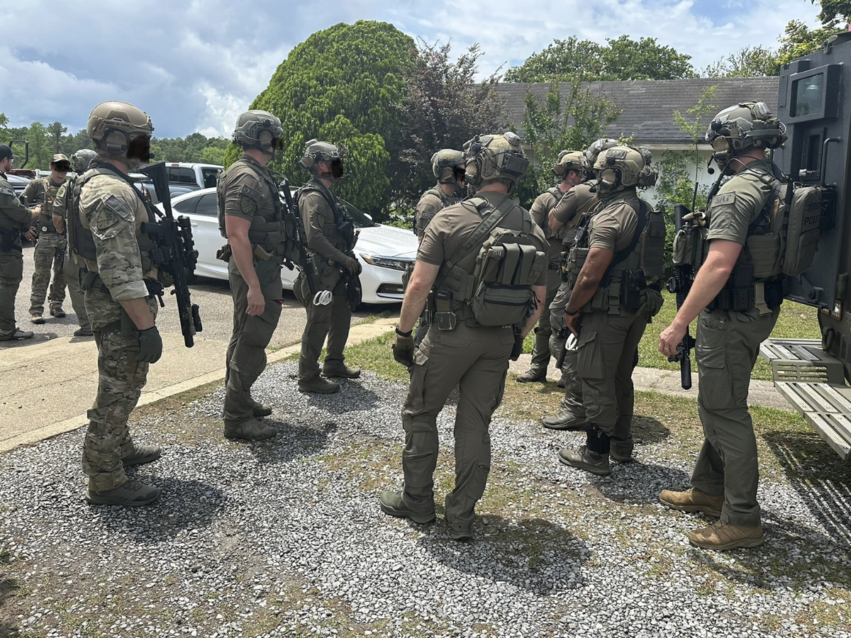 Law enforcement agents, whose faces have been blurred by U.S. Immigration and Customs Enforcement, at the scene of a cockfighting operation in Harrison County in 2025. 