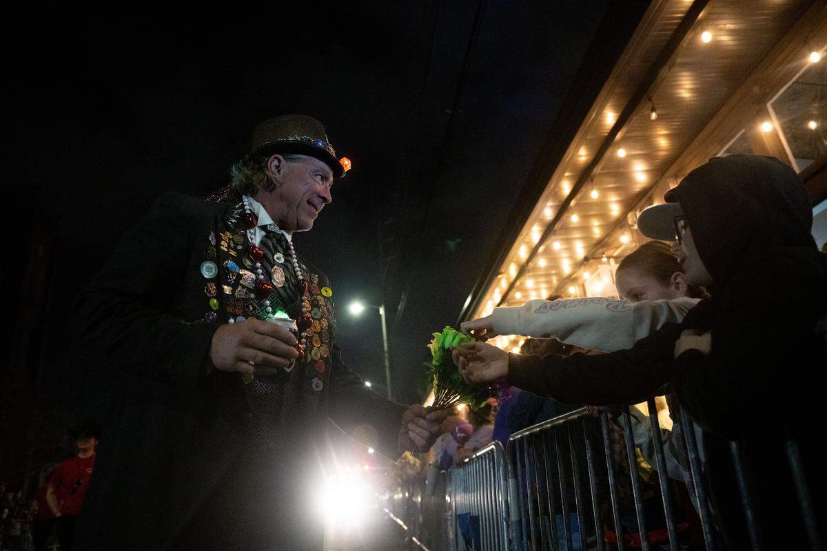 Parade participants pass out flowers to attendees during the Krewe of Neptune parade in Biloxi on Saturday, Feb. 14, 2026.