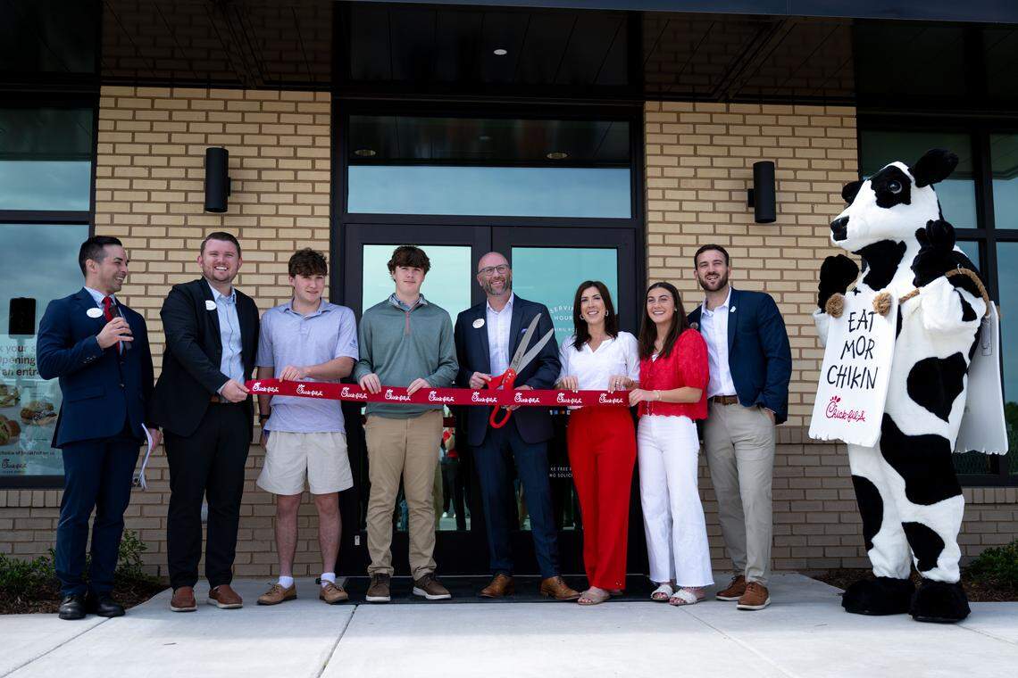 Owner-operator Craig Smith, middle, poses for a photos as he cuts a ceremonial Wednesday at the new Chick-Fil-A in Ocean Springs.
