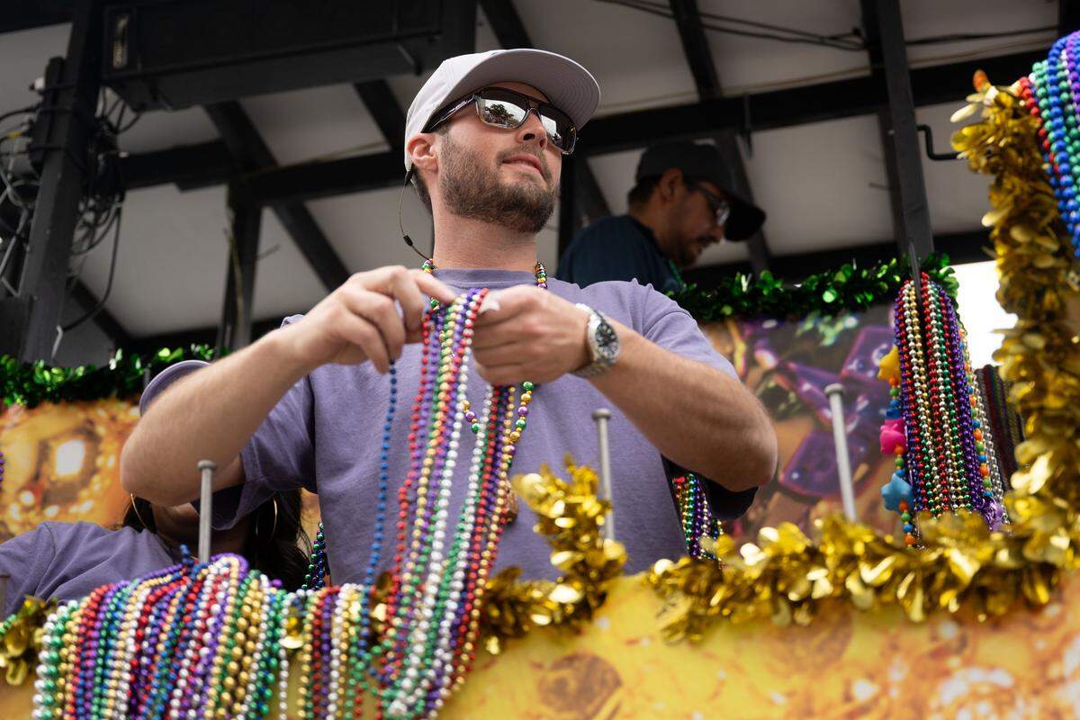A parade participant throws Mardi Gras beads from a float.
