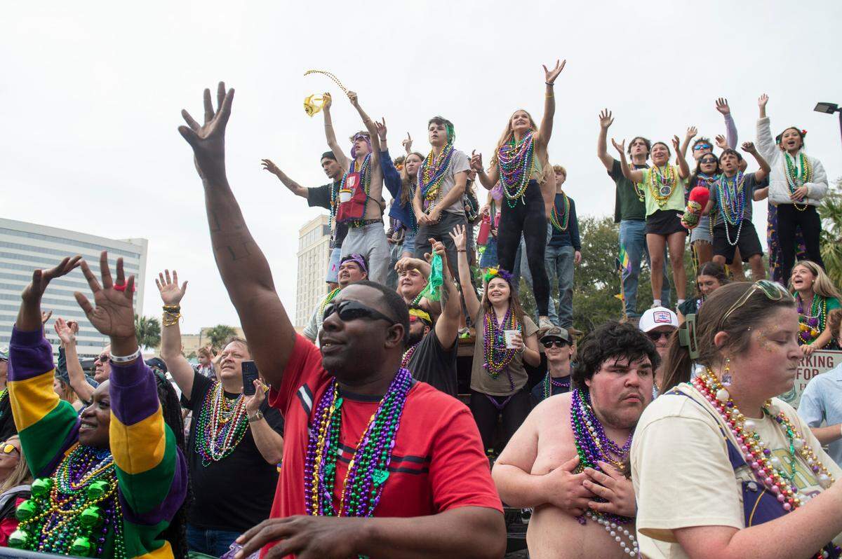 Parade watchers cheer for beads and other throws during the Gulf Coast Carnival Association Mardi Gras parade in Biloxi on Tuesday, March 4, 2025.