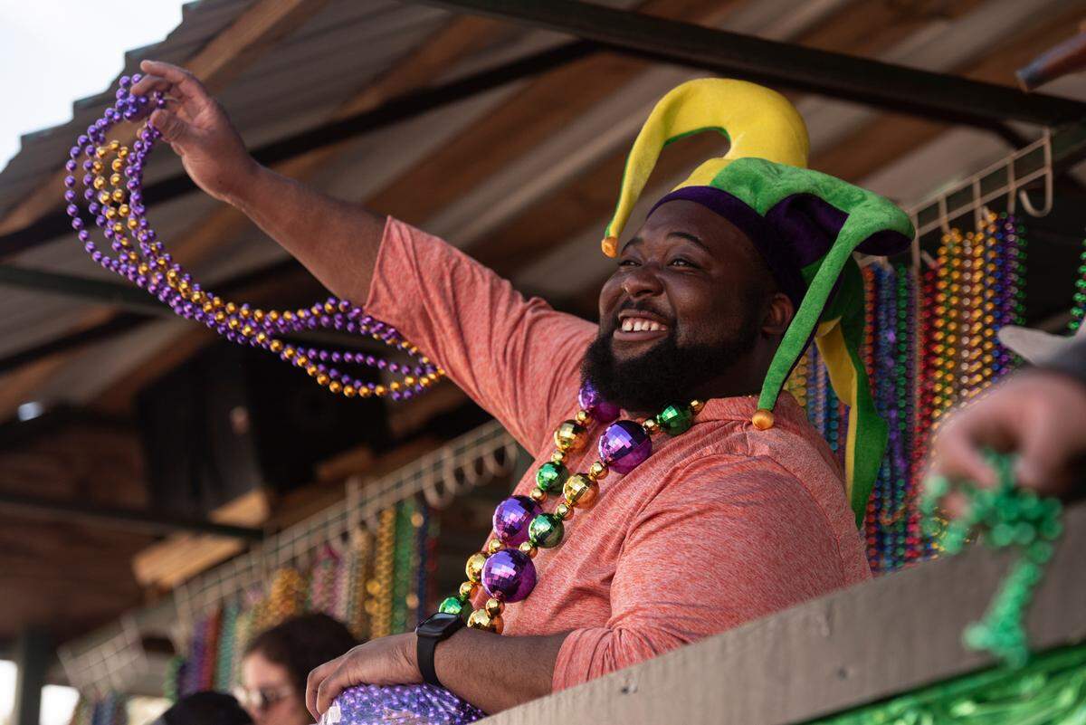 A float rider throws beads during the Gulf Coast Carnival Association’s Mardi Gras parade in Biloxi on Tuesday, Feb. 13, 2024.
