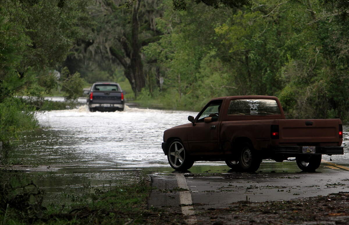 A truck waits at the edge of a large pool of water blocking Highway 604 in Pearlington on Thursday, Aug. 30, 2012, one day after Hurricane Isaac’s final landfall in Louisiana.