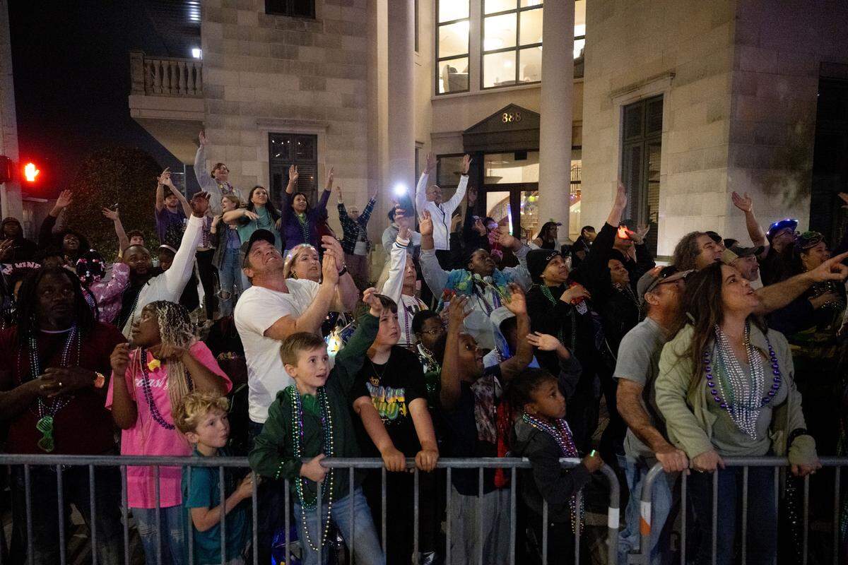 A crowd of parade attendees cheer on as parade floats drive through Howard Avenue during the Krewe of Neptune parade in Biloxi on Saturday, Feb. 14, 2026.