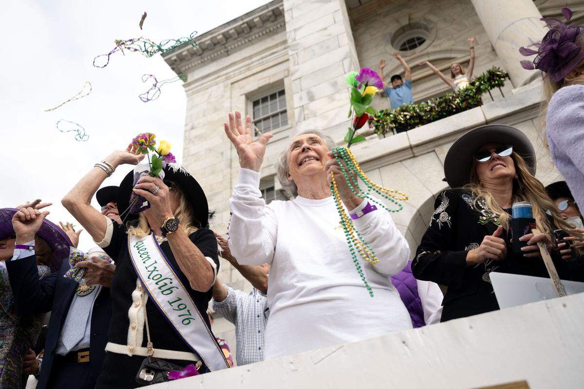 Members of the crowd cheer as they reach out to catch throws from floats.