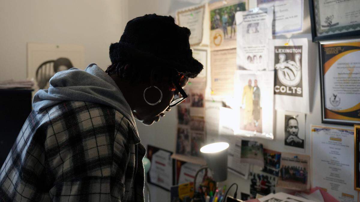 This photo provided by the University of Maryland shows Sherri Reeves looking through a collection of photos and clippings from the Lexington Colts, a youth football organization that she runs with her sons, Peter and Paul, at her home in Lexington, Miss., Jan. 3, 2024. (University of Maryland/Jenna Bloom via AP)