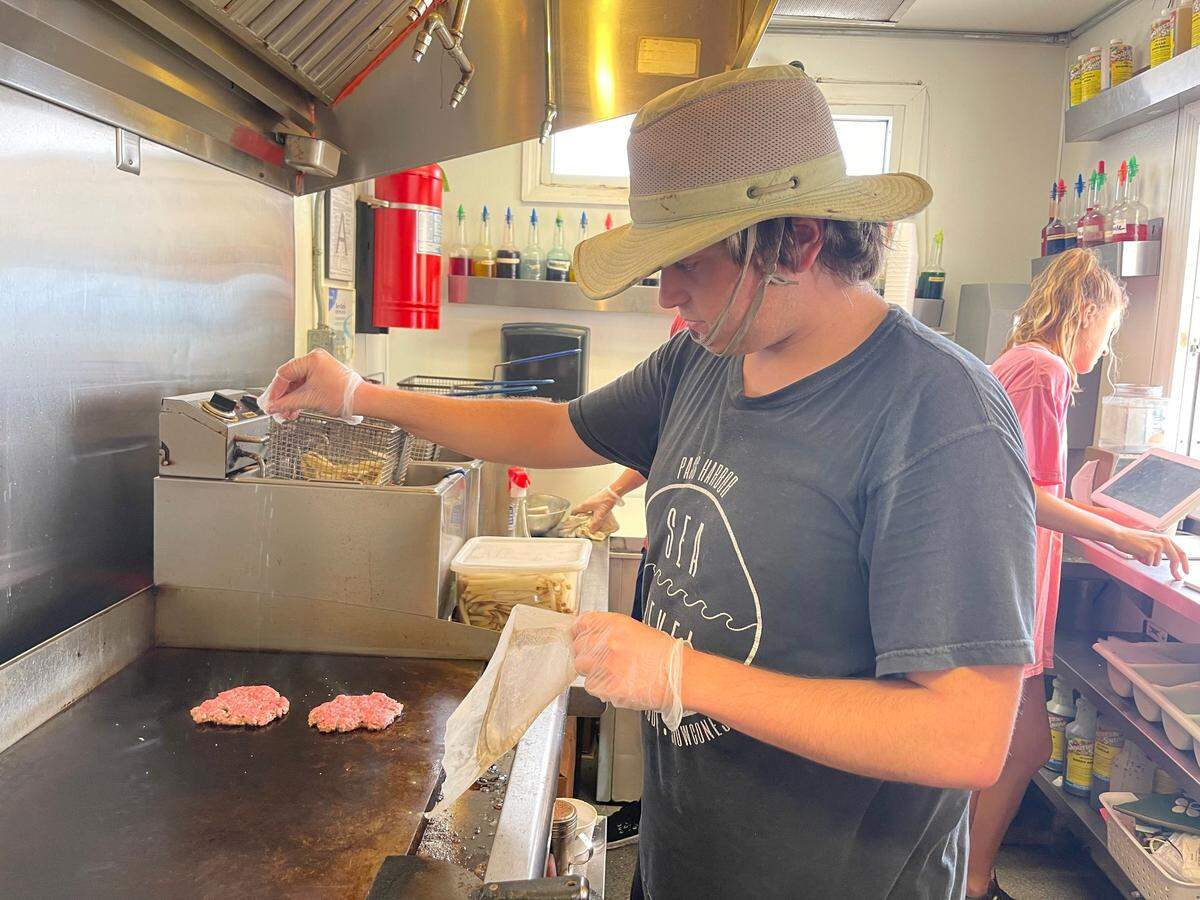 Sea Level manager Kyle Thomas prepares a burger at the snack shack in the Pass Christian Harbor. He is the new owner of the restaurant in the West Pass Harbor.