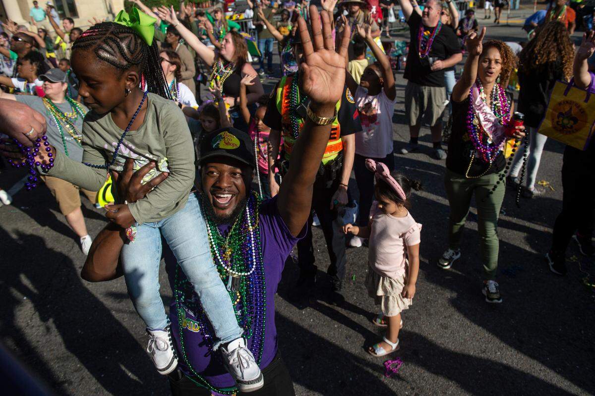 A man holds a little girl up to a float to get beads during the Gulf Coast Carnival Association Mardi Gras parade in Biloxi on Tuesday, Feb. 21, 2023.
