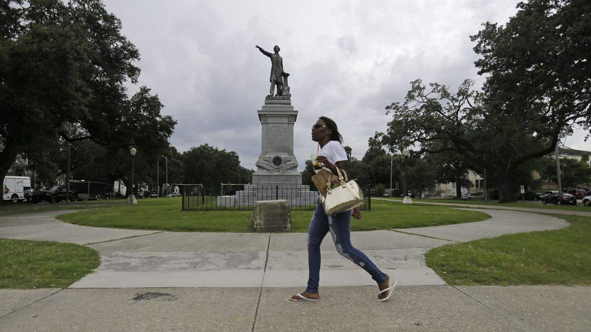 FILE - In this Sept. 2, 2015 file photo, a woman walks past a monument of Jefferson Davis on Jefferson Davis Parkway at Canal Street in New Orleans. Prominent Confederate monuments long taken for granted on the streets of this Deep South city may be on the verge of coming down and become new examples of a mood taking hold nationwide to erase racially charged symbolism from public view, which is among the state's top stories of 2015. (AP Photo/Gerald Herbert, File)