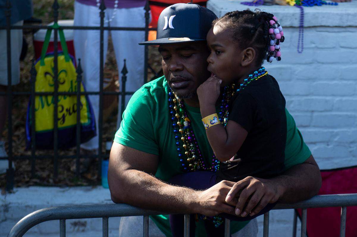 A man and his daughter watch the parade together during the Gulf Coast Carnival Association Mardi Gras parade in Biloxi on Tuesday, Feb. 21, 2023.