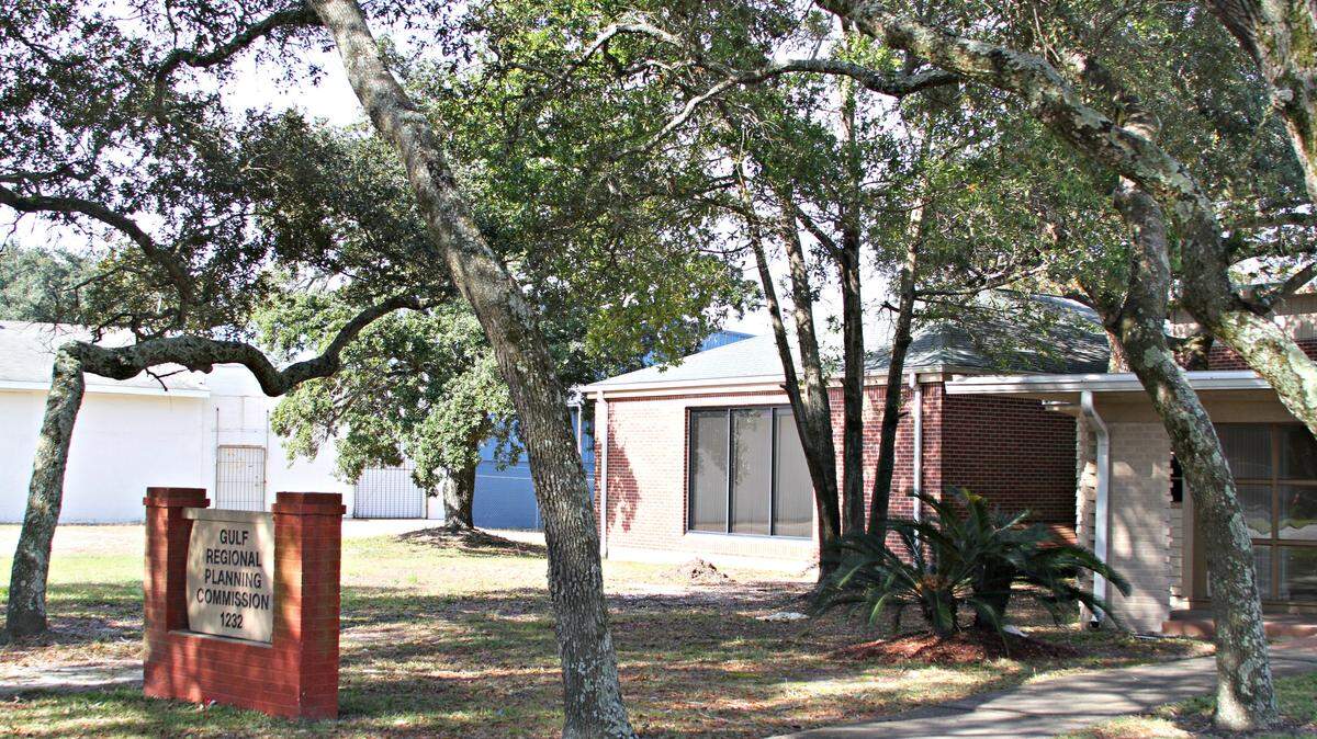 ANITA LEE/SUN HERALD 
 Pictured are three of the five Live oaks a property owner wants to remove from this Pass Road business lot: the tree at the far left and trees on each side of the sidewalk.
