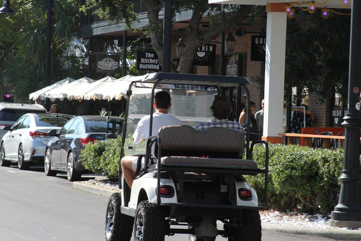 A couple takes in the sights along Government Street in a golf cart, an increasingly common mode of transportation in downtown Ocean Springs.