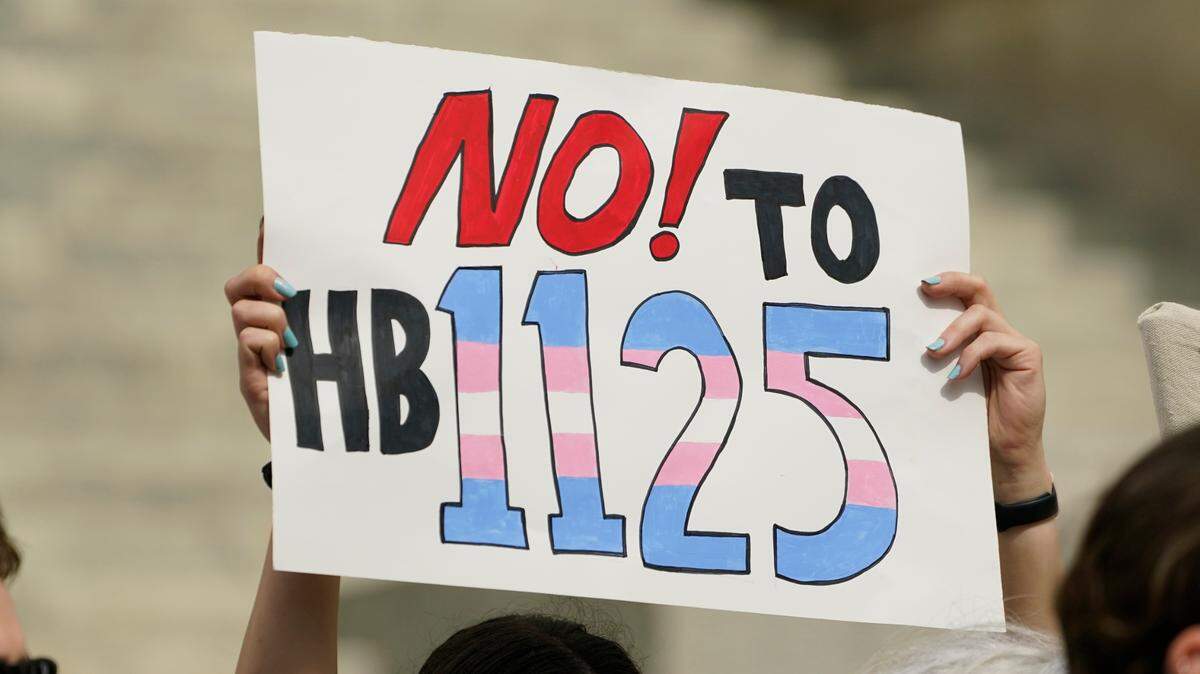 A protester holds a poster calling for lawmakers to vote against House Bill 1125, which would ban gender-affirming care for trans children at the Mississippi Capitol in Jackson, Wednesday, Feb. 15, 2023. (AP Photo/Rogelio V. Solis)